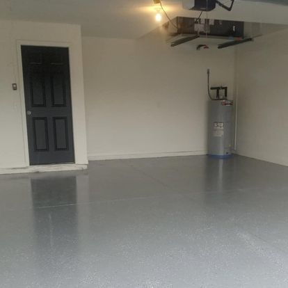 An empty garage with a black door and a water heater.