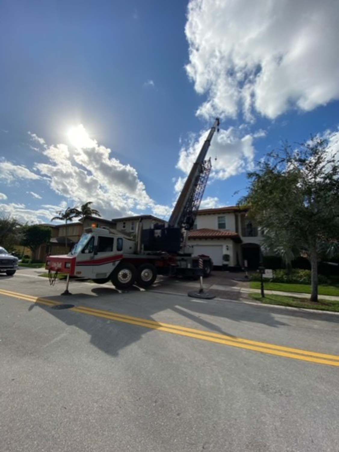 A crane is parked on the side of the road in front of a house.