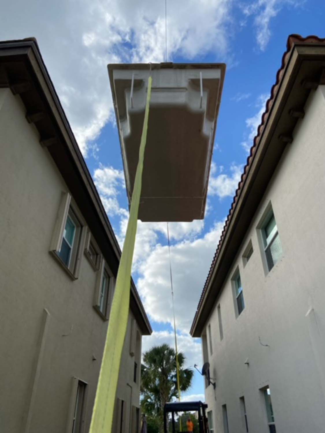A crane is lifting a swimming pool between two buildings