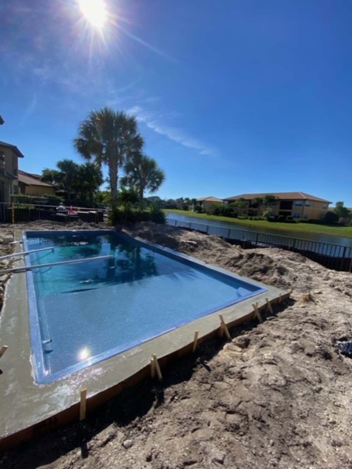 A large swimming pool is being built in the backyard of a house.