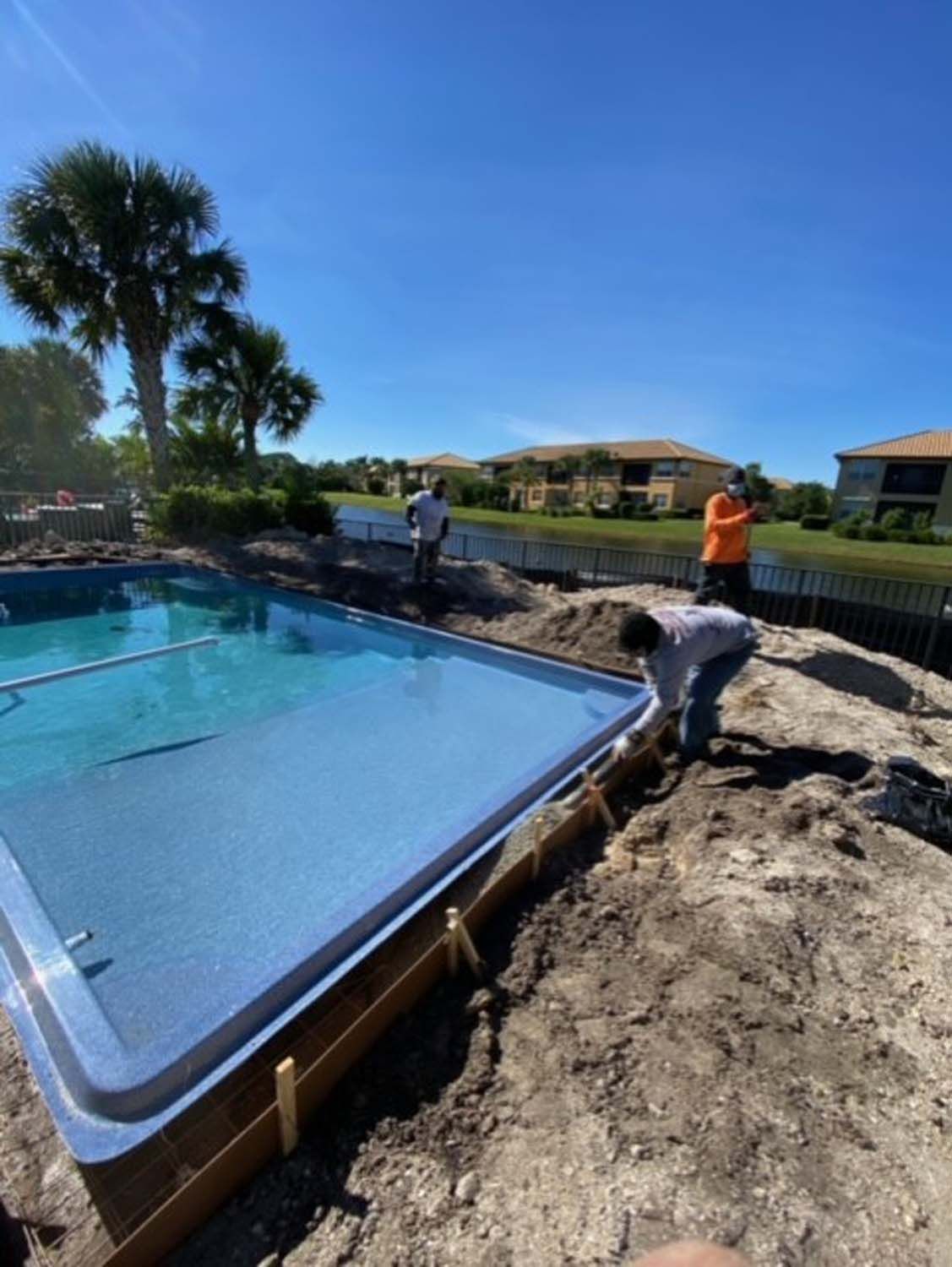 Two men are working on a swimming pool in the dirt