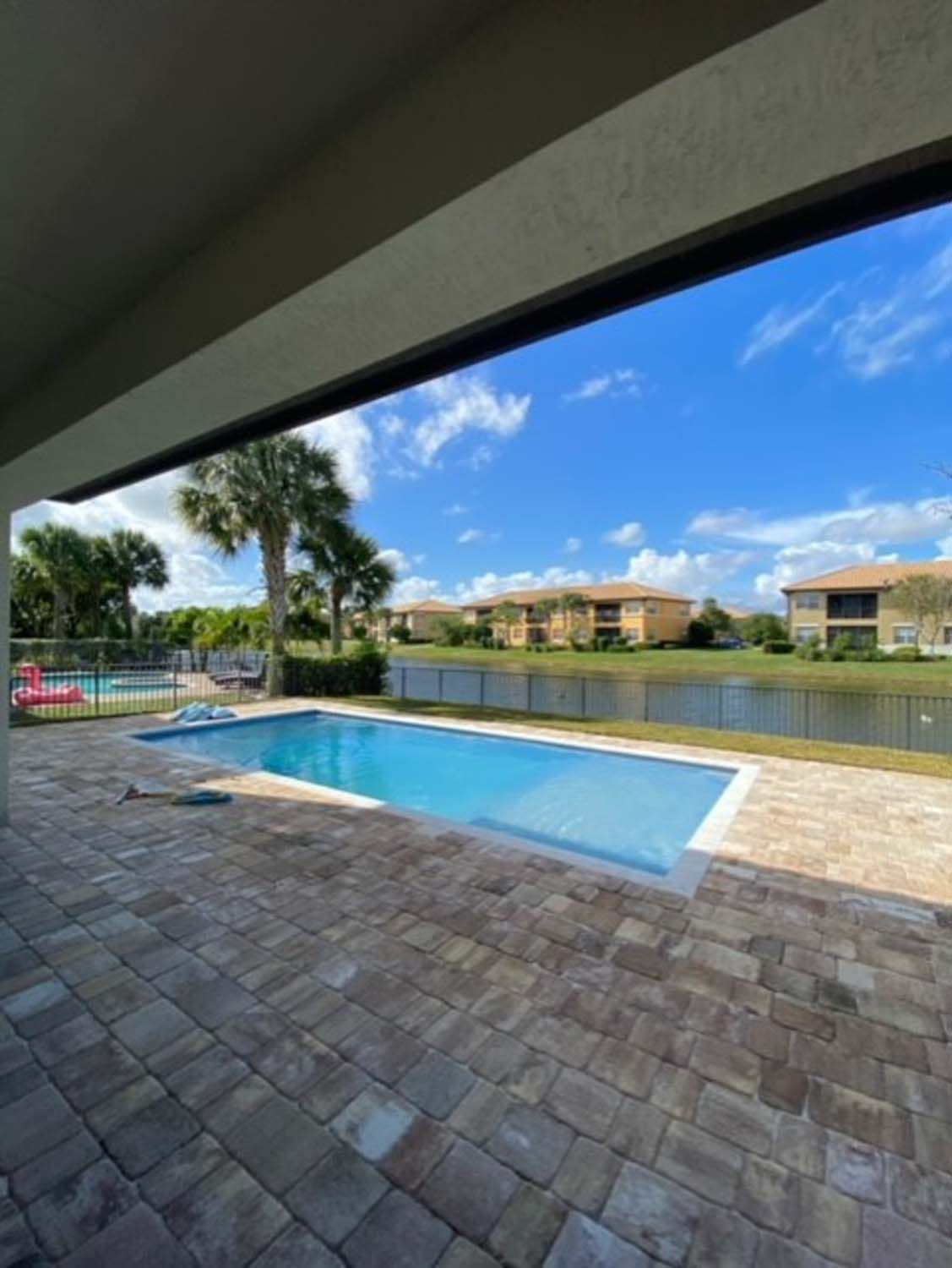 A large swimming pool is surrounded by houses and palm trees