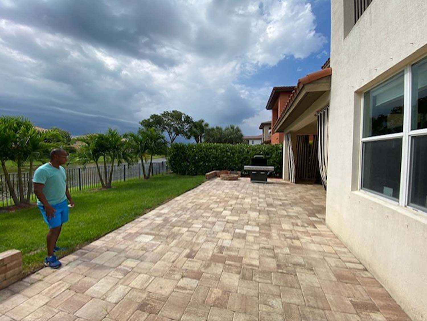 A man is standing on a brick patio in front of a house.
