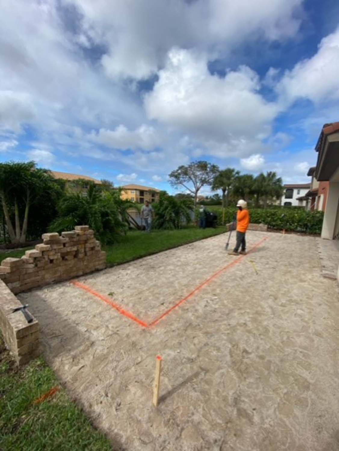 A man is standing in the dirt in front of a house.