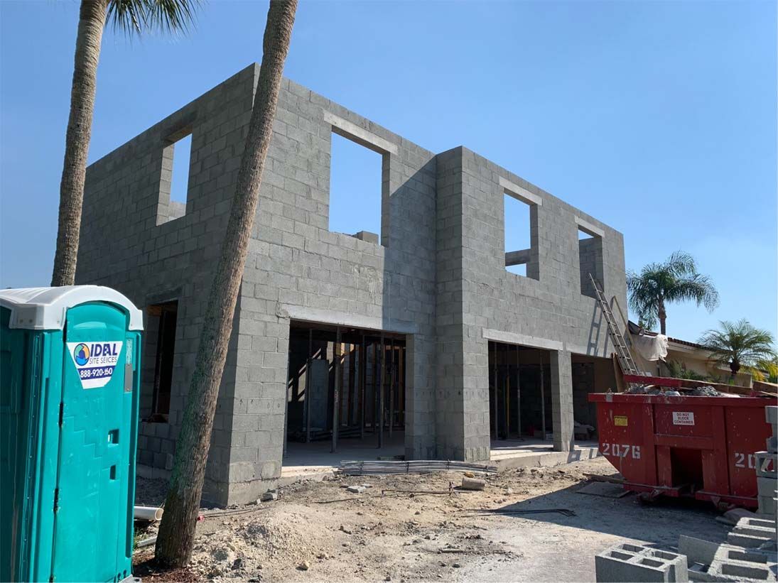 A portable toilet is sitting in front of a building under construction.