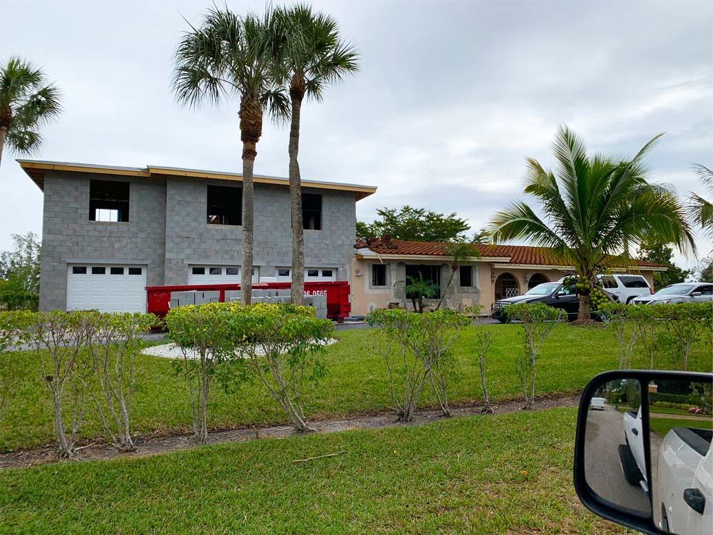 A white car is parked in front of a house under construction.