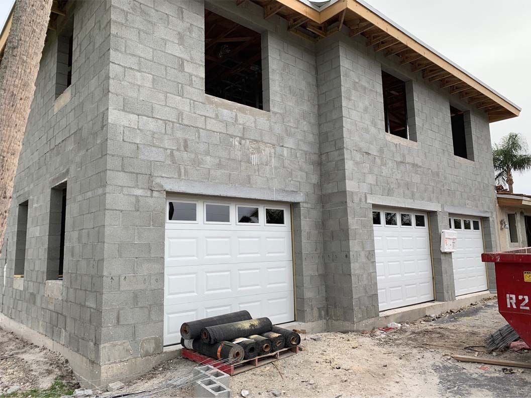 A house is being built with bricks and white garage doors.