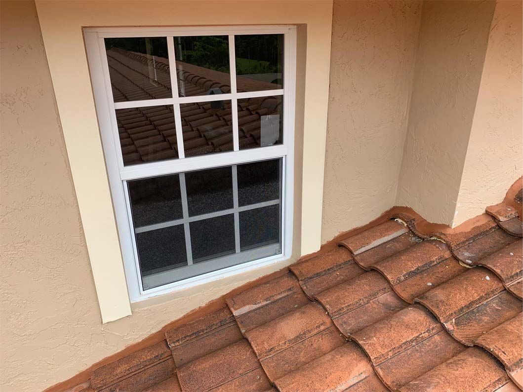 A window on the side of a house next to a tiled roof.