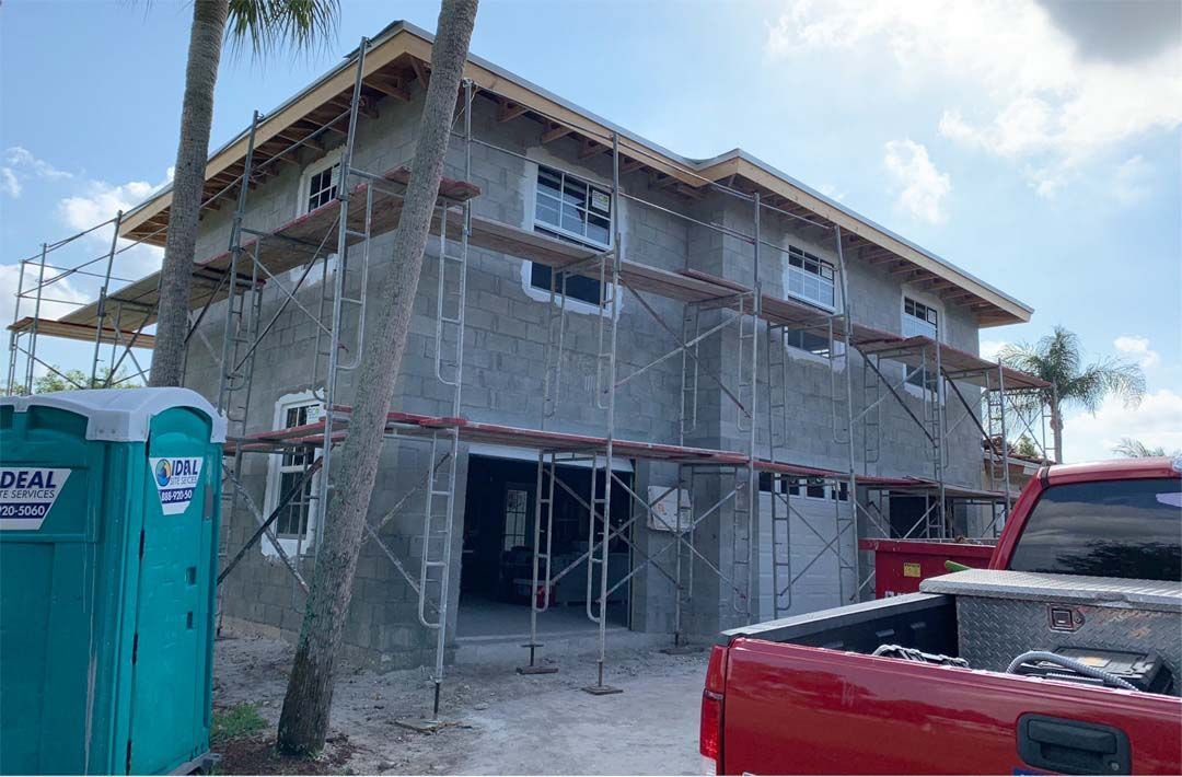A red truck is parked in front of a house under construction.