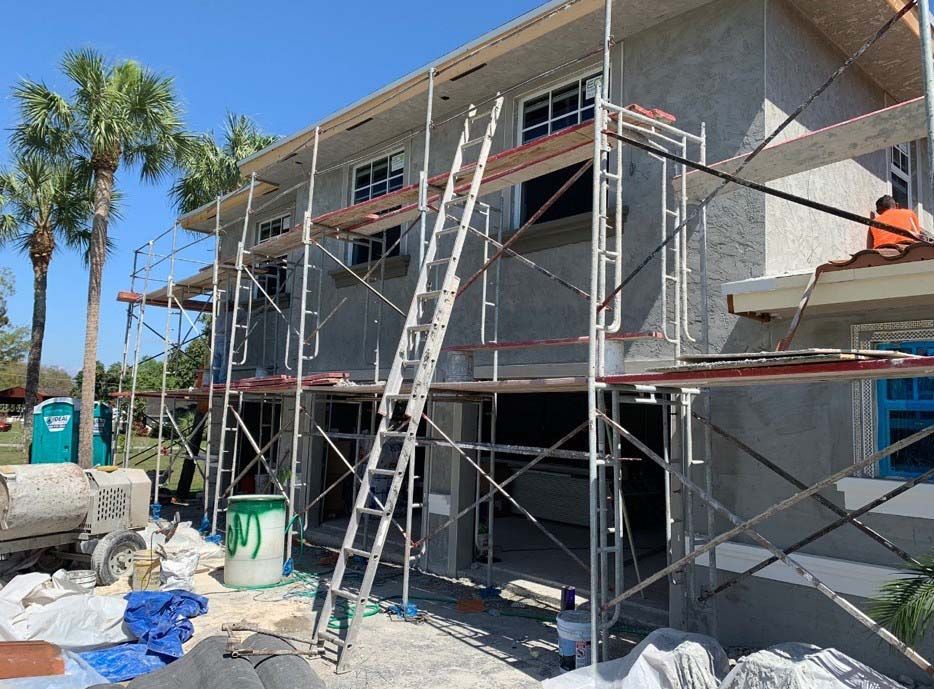 A house is being built with scaffolding and a ladder.