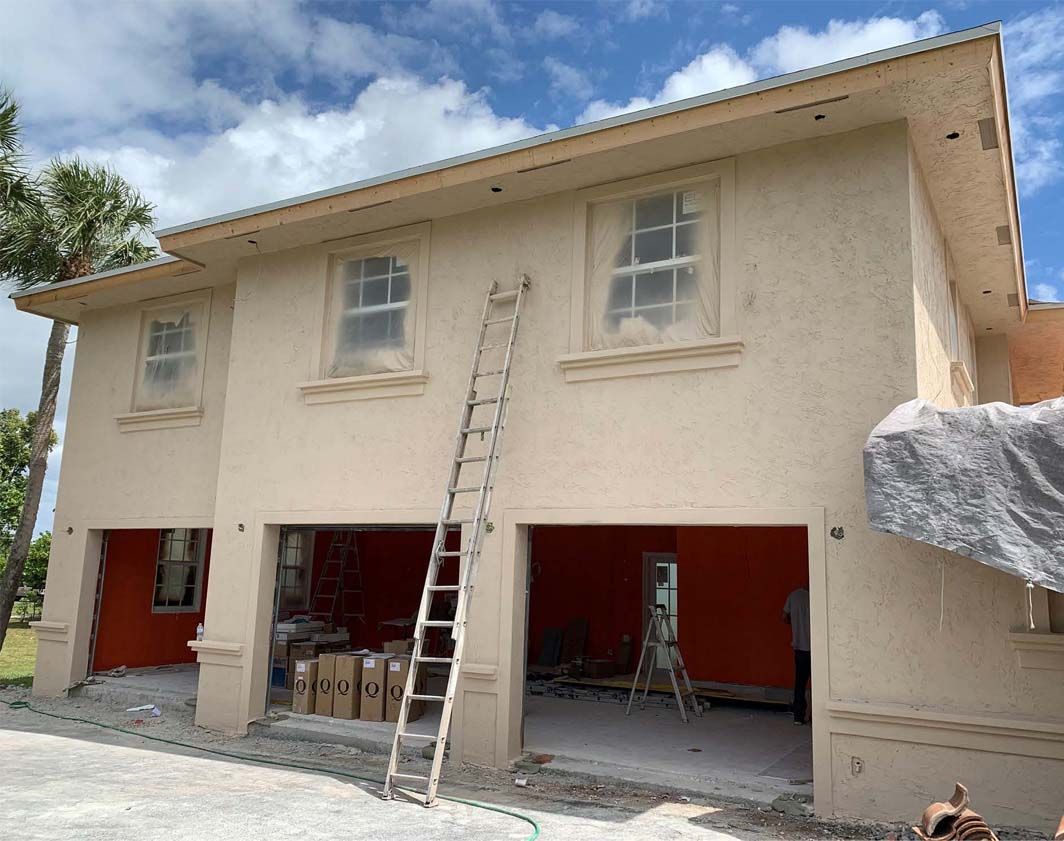 A house is being painted with a ladder in front of it.