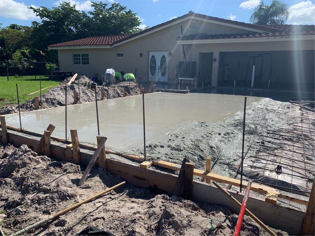 A concrete driveway is being built in front of a house.
