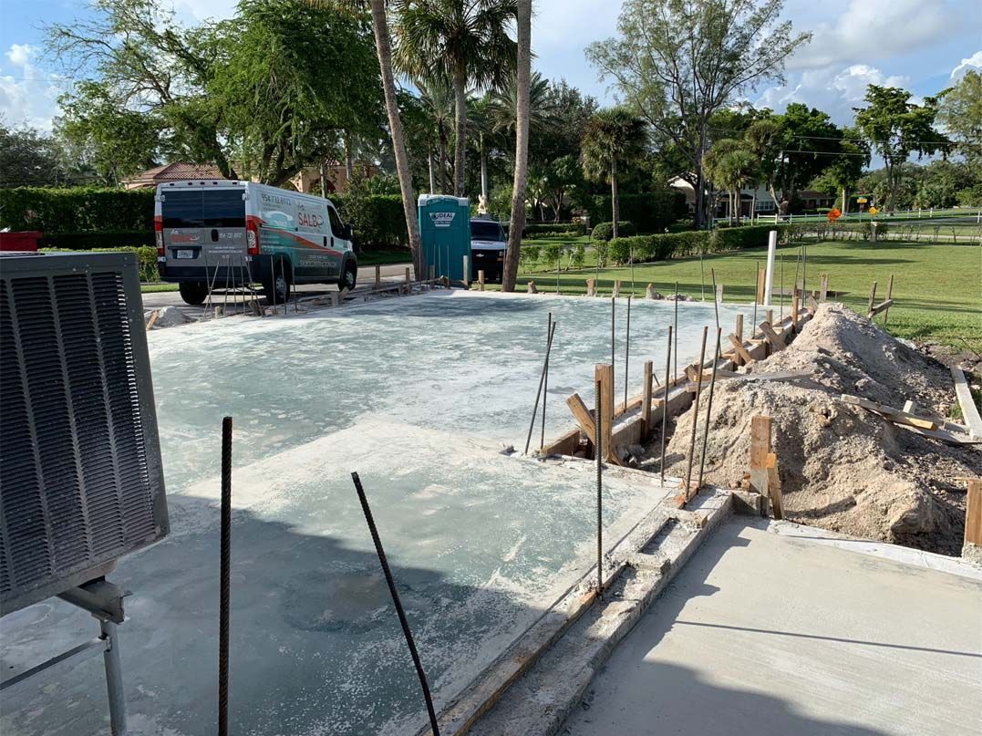 A concrete driveway is being built in a yard with a van in the background.