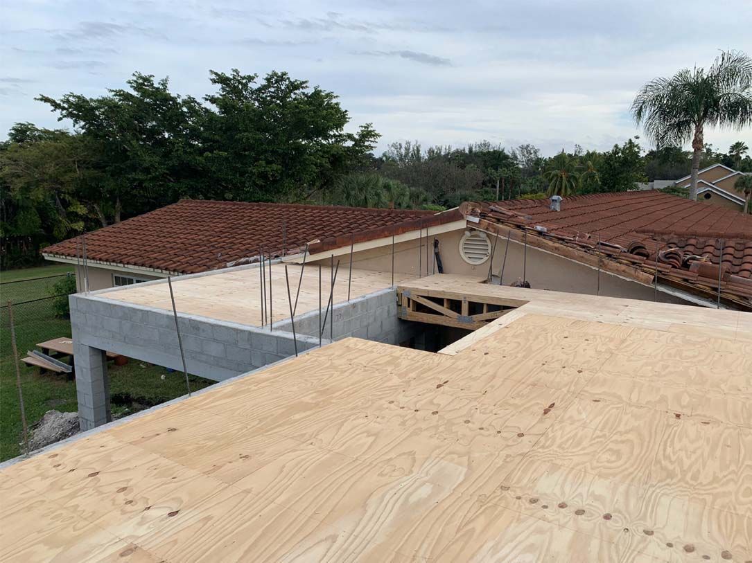 The roof of a house is being built and there is a lot of plywood on the roof.