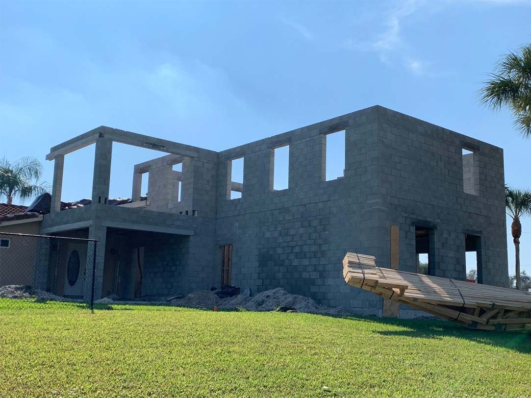 A large concrete house is being built in a grassy field.