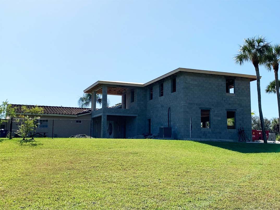 A large house is being built in a grassy field.