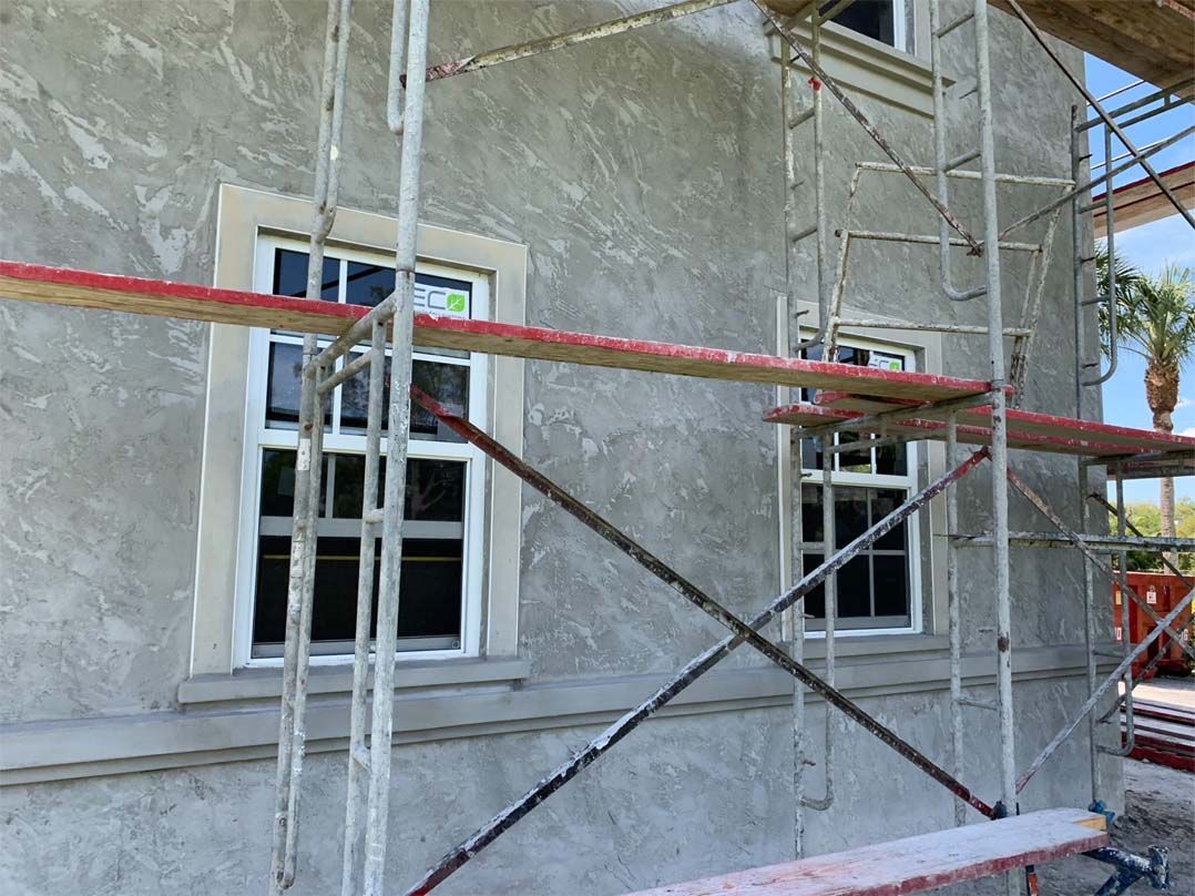 A building under construction with scaffolding around it and two windows.
