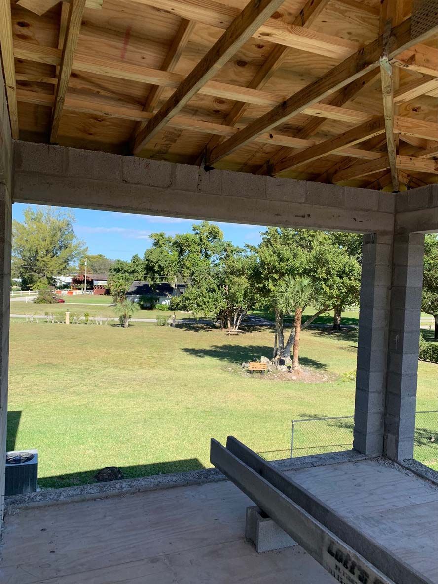 A building under construction with a view of a grassy field.