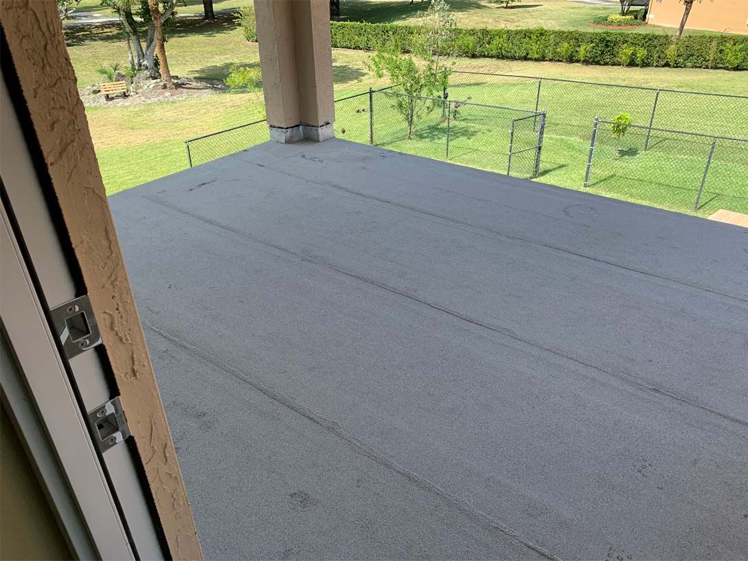 A view of a patio from a window with a fence in the background.