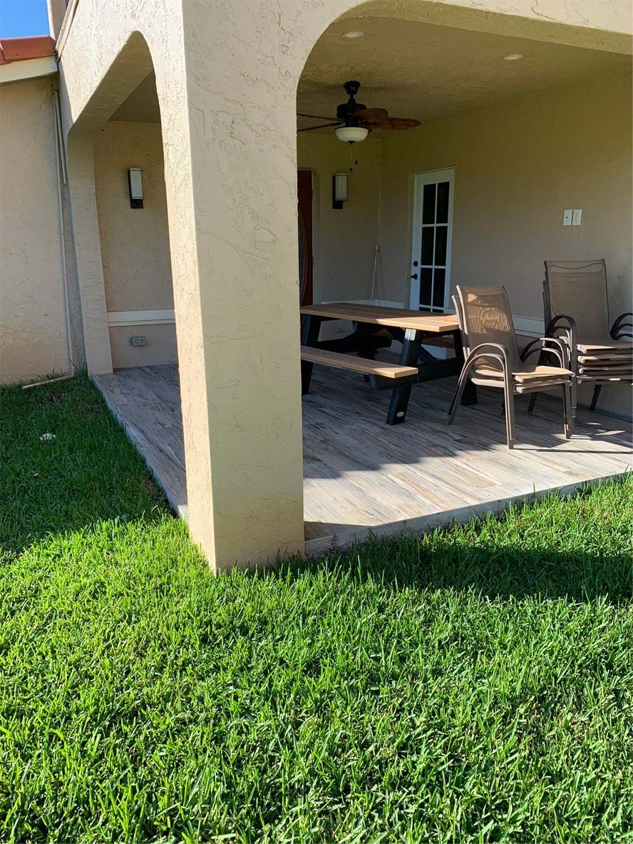 A patio with a picnic table and chairs under a ceiling fan