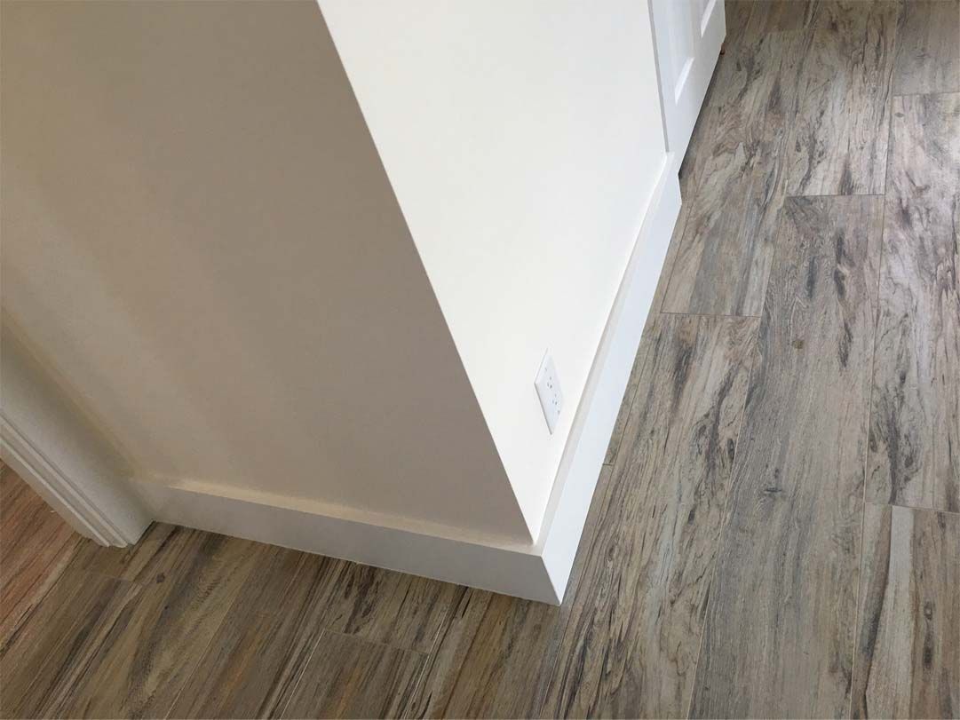 A close up of a wooden floor in a room with a white wall.