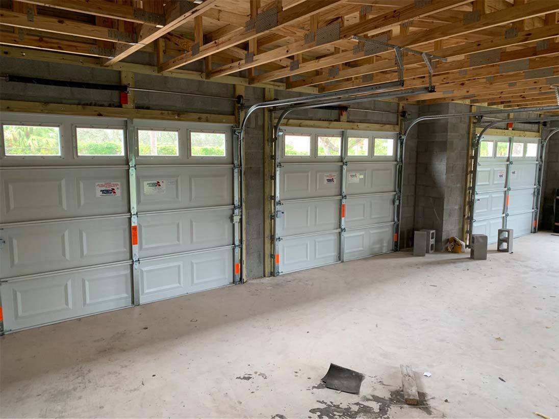 A garage with two garage doors open in a house under construction.
