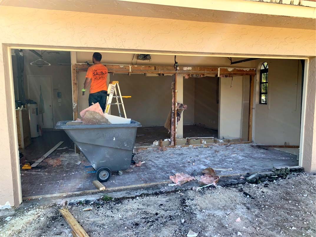 A man is standing in a garage next to a wheelbarrow.