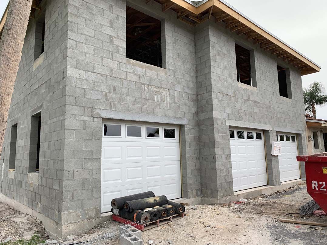 A house is being built with bricks and white garage doors.