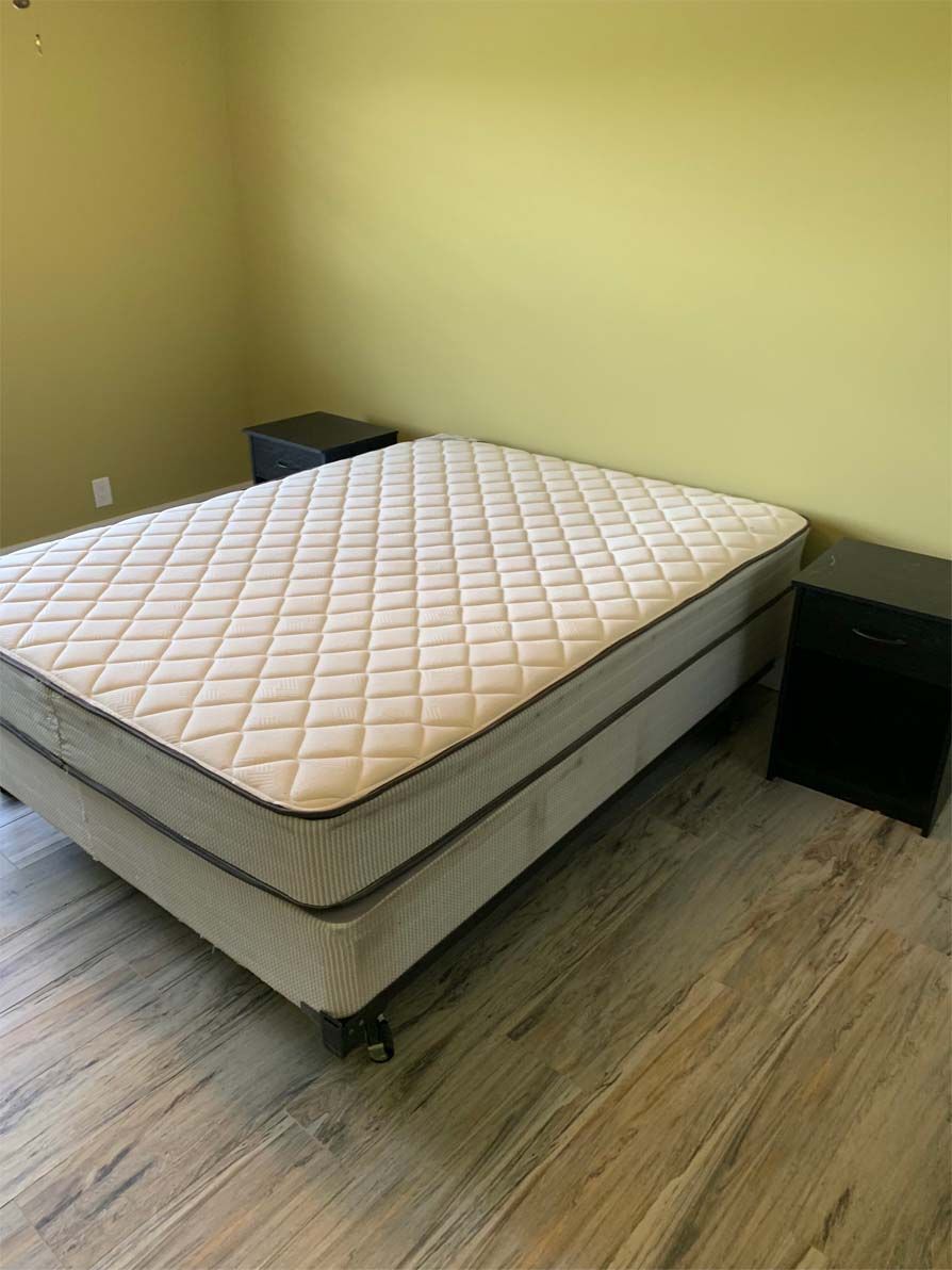A bed with a mattress and two nightstands in a bedroom.