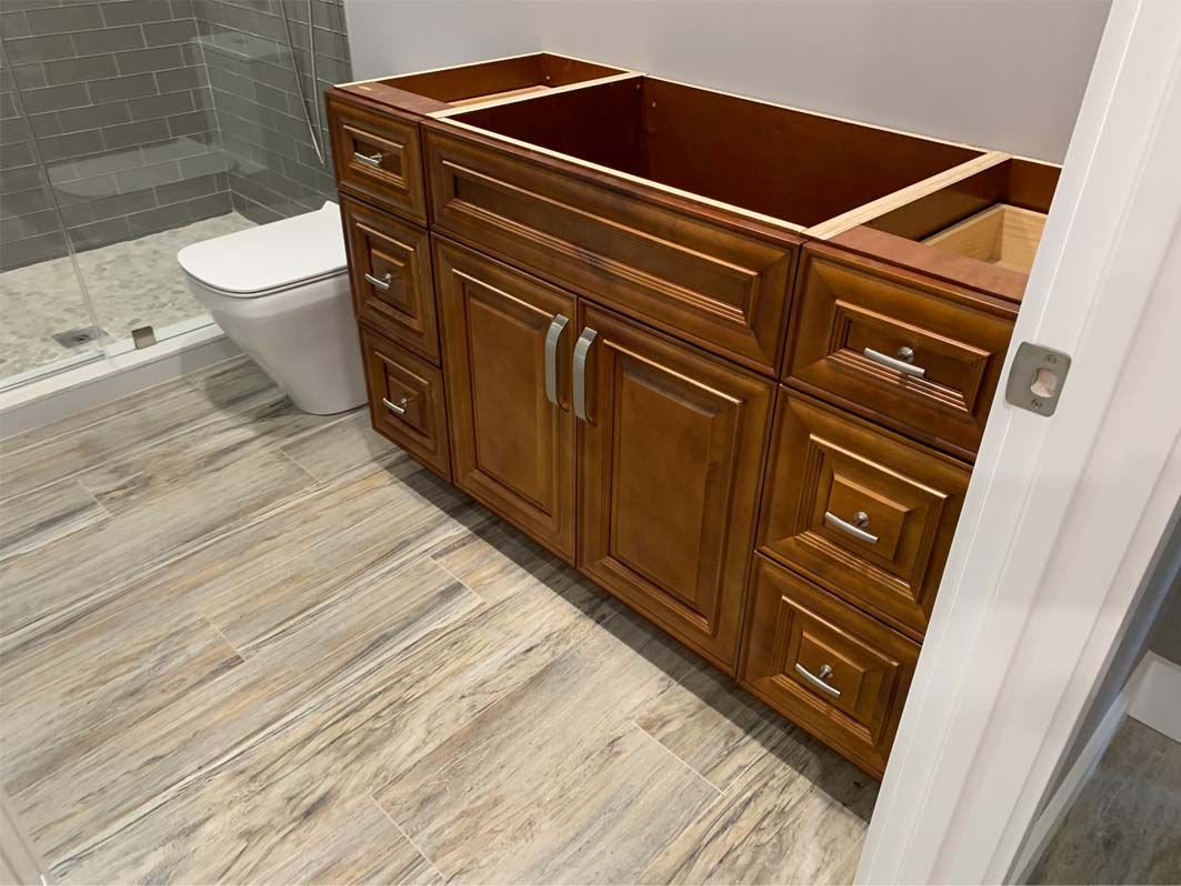 A bathroom with a sink , toilet and wooden cabinets.