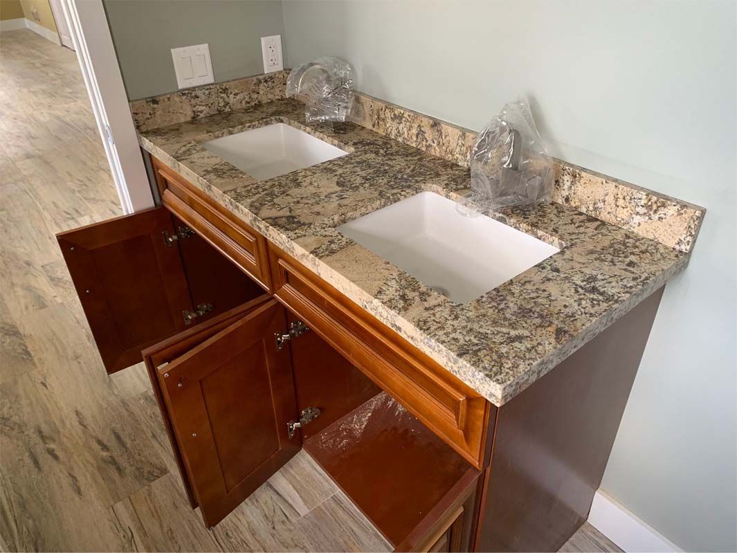 A bathroom vanity with two sinks and granite counter tops.