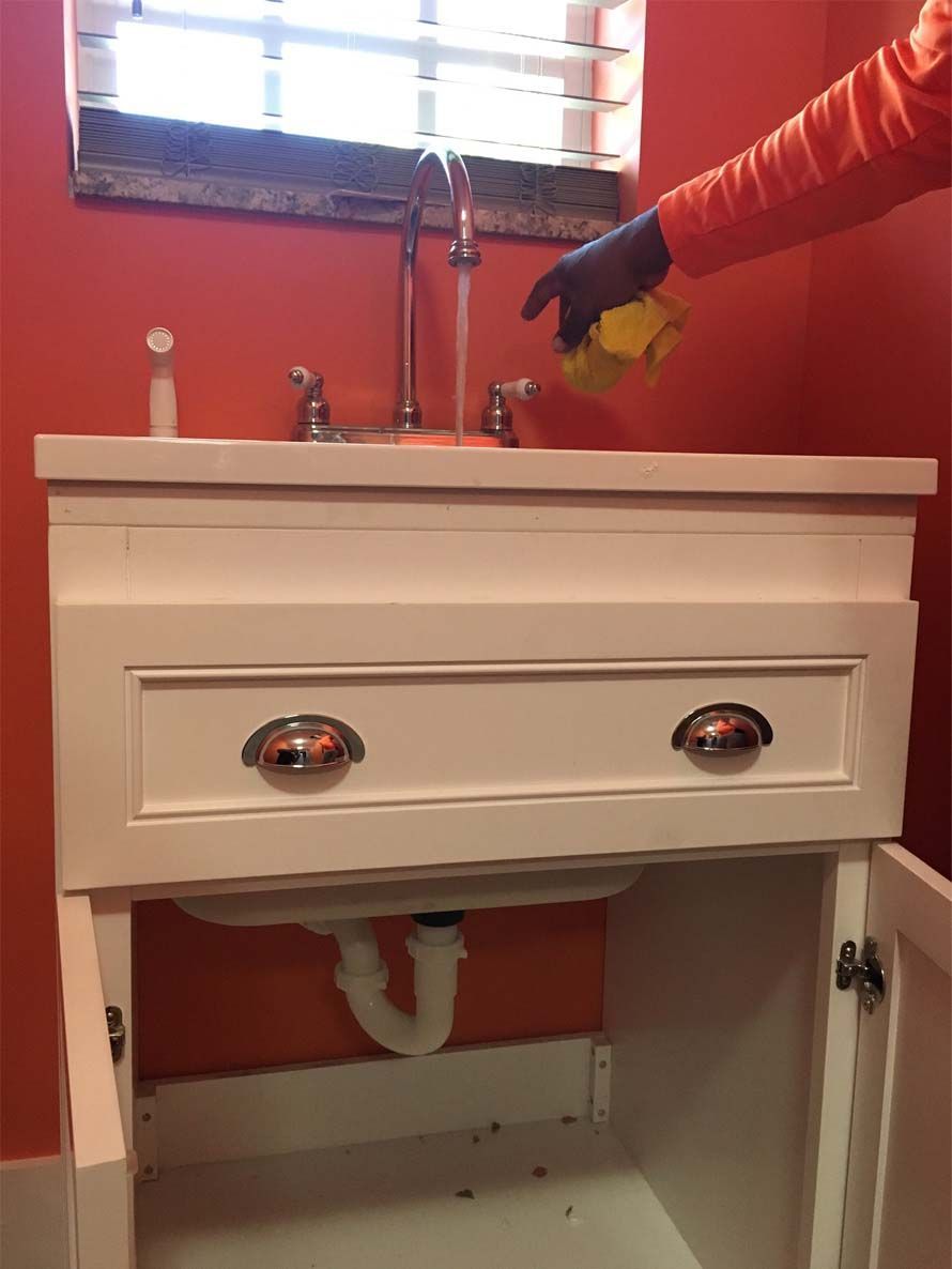 A person is cleaning a bathroom sink with a cloth