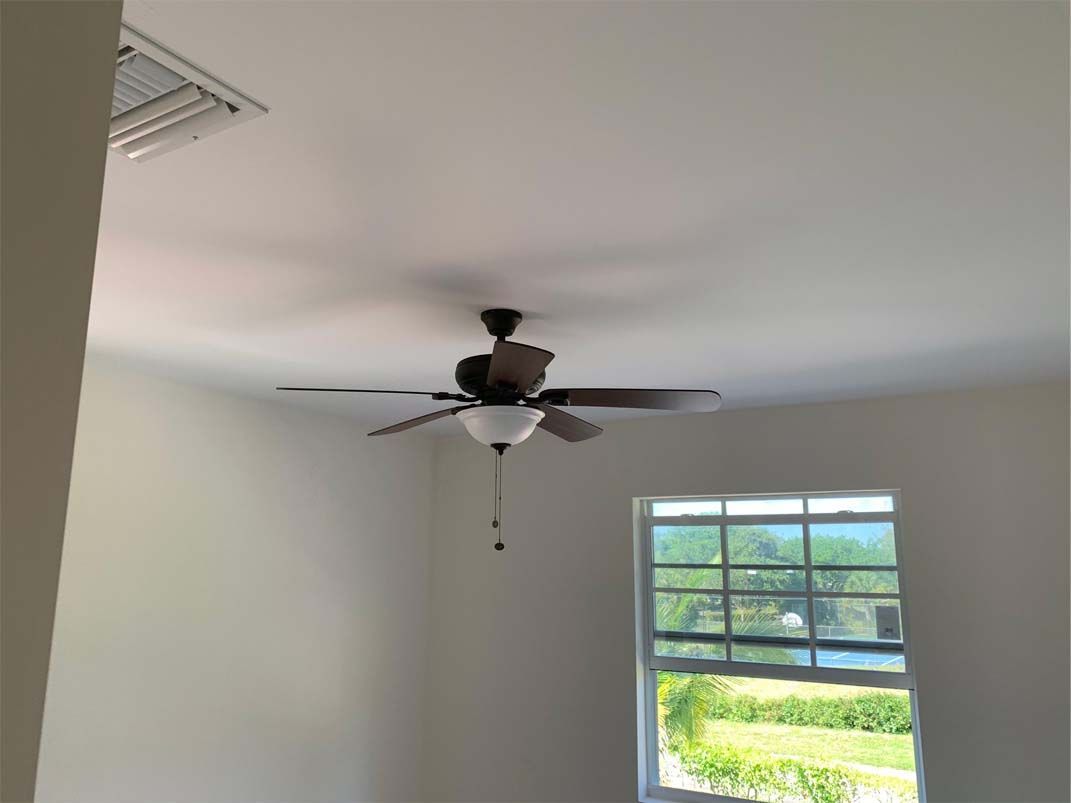 A room with a ceiling fan and a window.