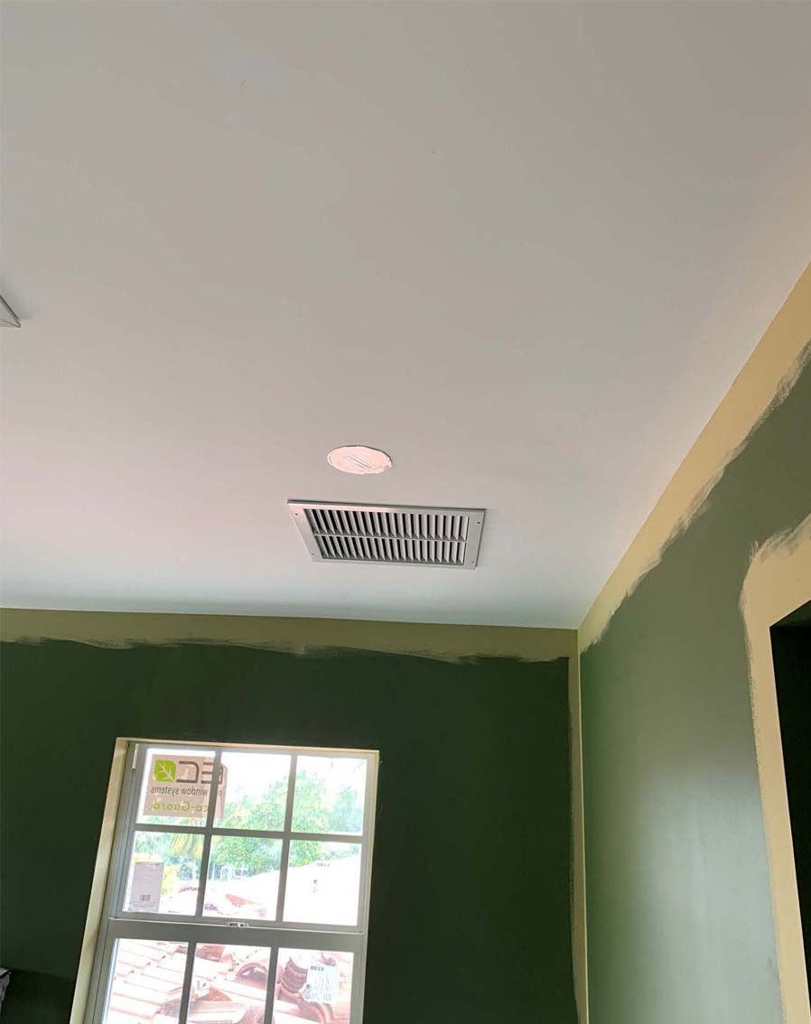 A room with green walls and a white ceiling with a window.