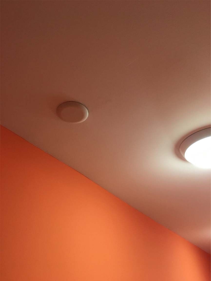 A close up of a ceiling with an orange wall and a light on it.