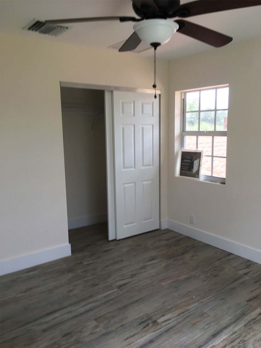 An empty room with a ceiling fan and a window