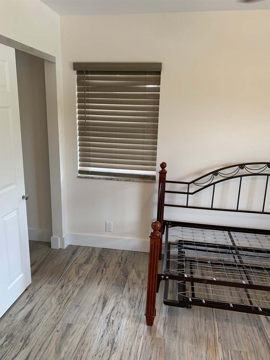 A bedroom with a bed and a window with blinds.