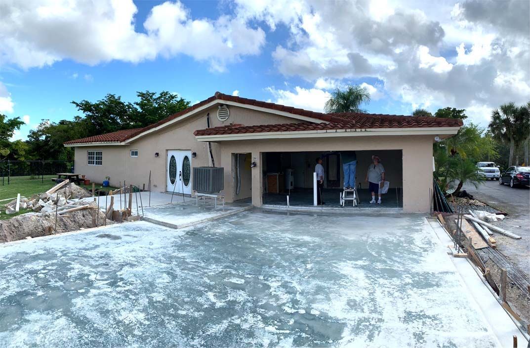 A house under construction with a concrete driveway in front of it.
