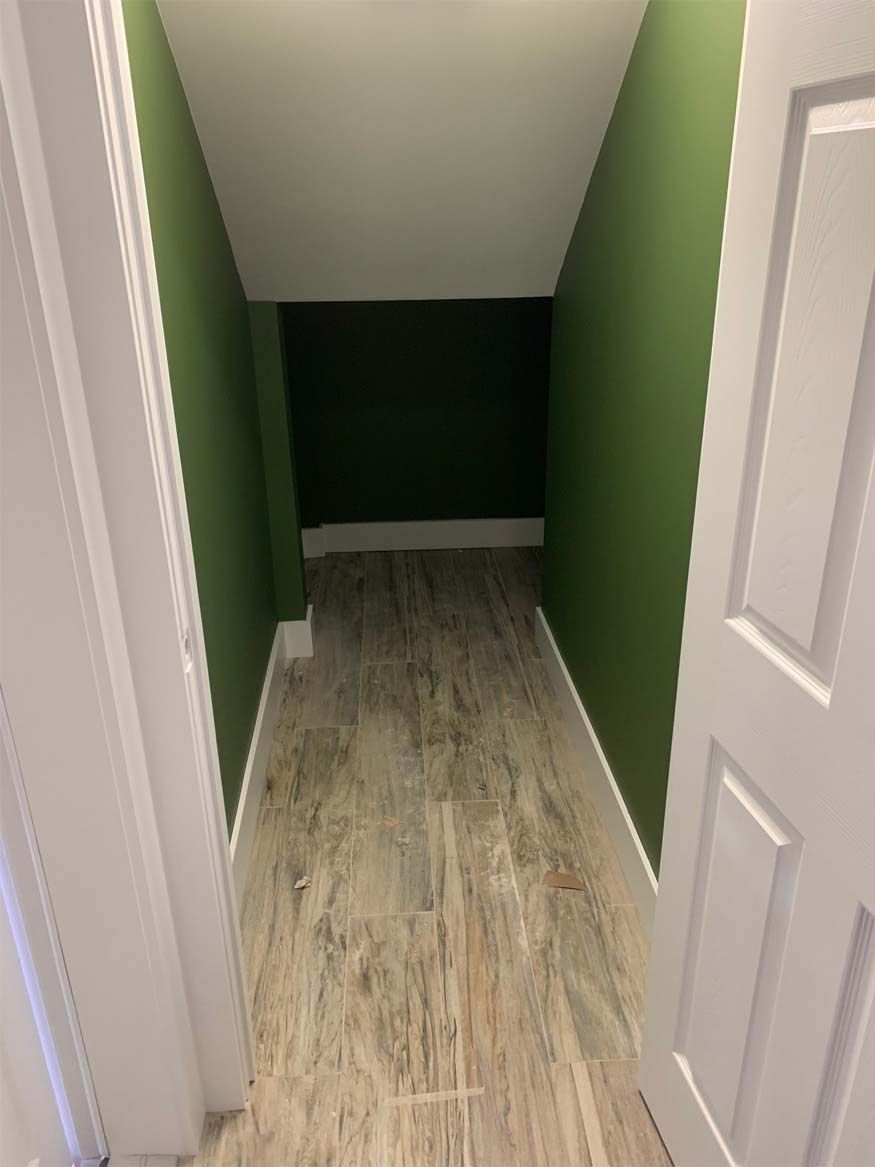 A narrow hallway with green walls and a white door.
