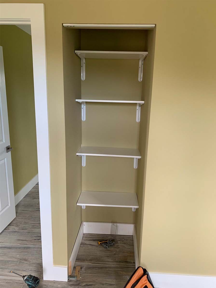 A closet with shelves and a door in a room.