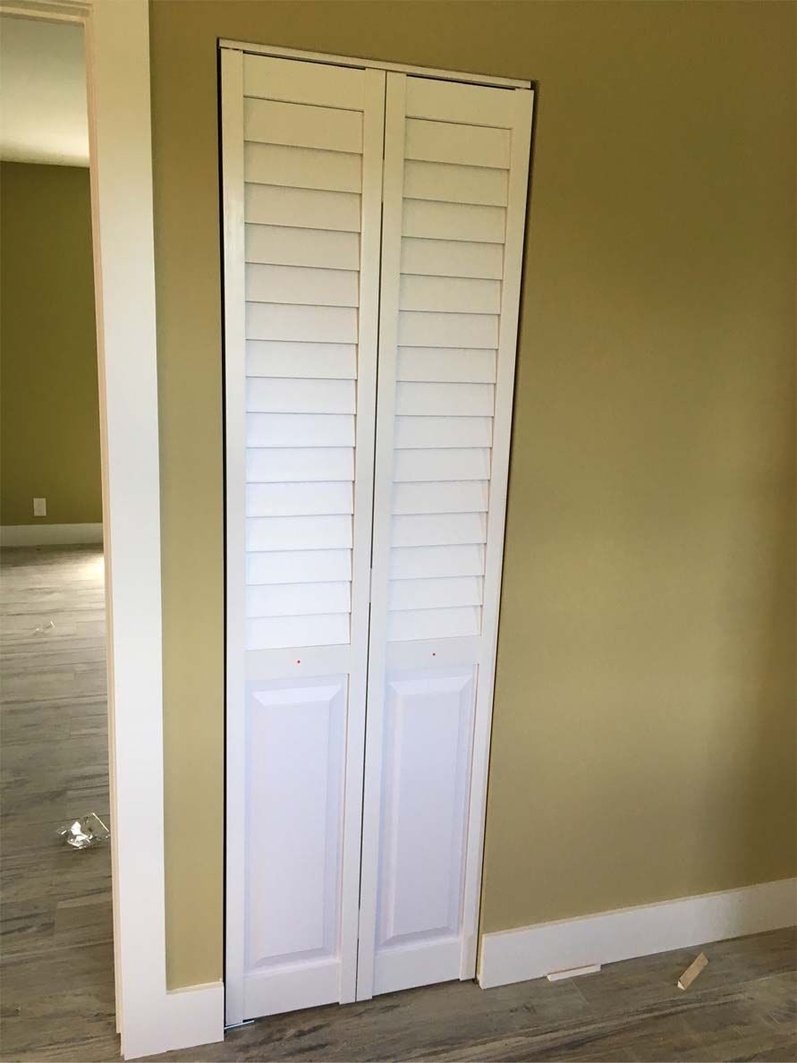 A pair of white shutters on a door in an empty room.