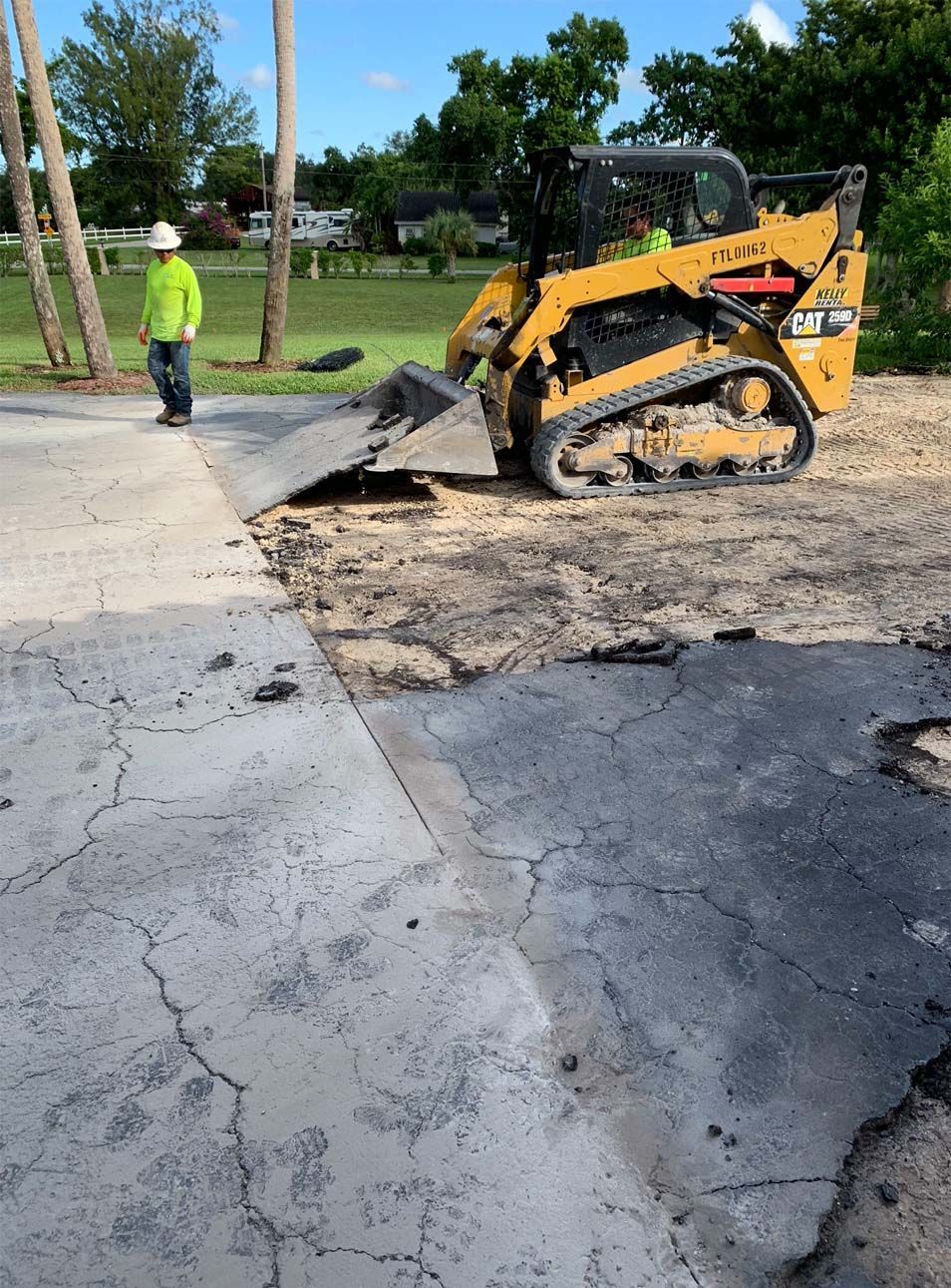 A man is standing next to a yellow cat bulldozer