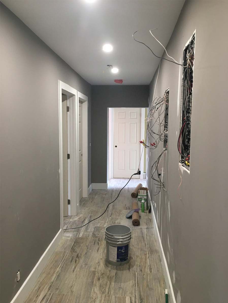 A long hallway with a bucket of paint on the floor.