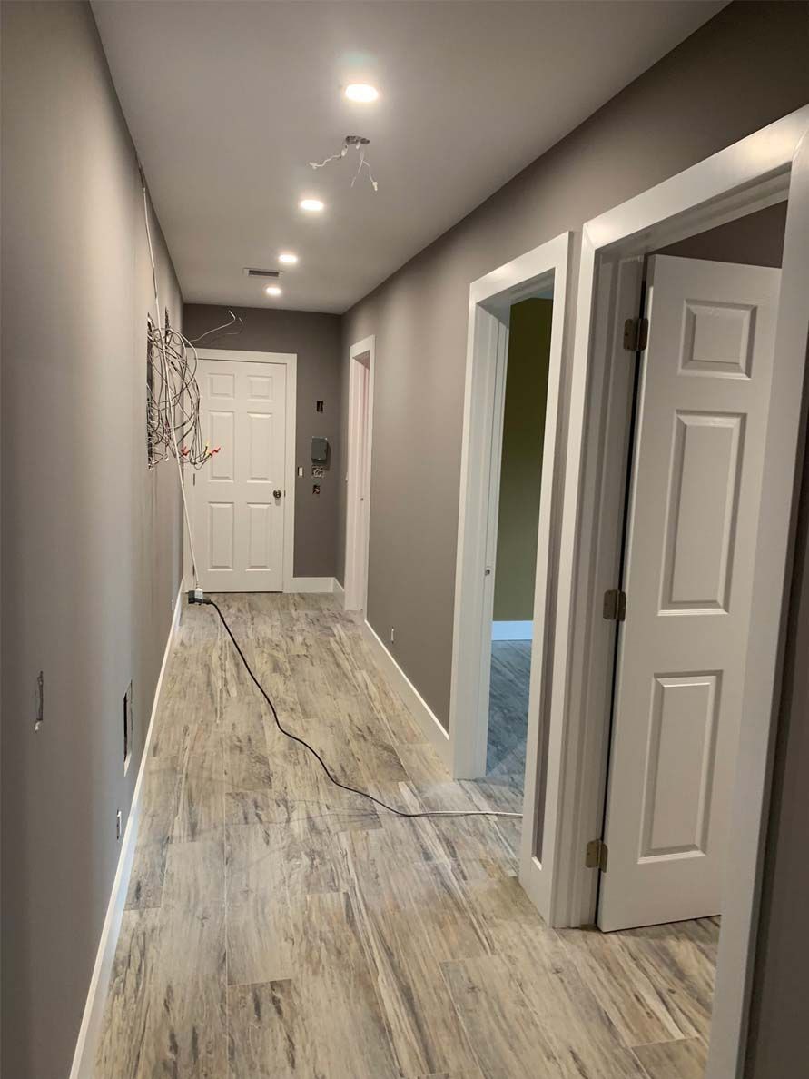 A long hallway with hardwood floors and white doors in a house.