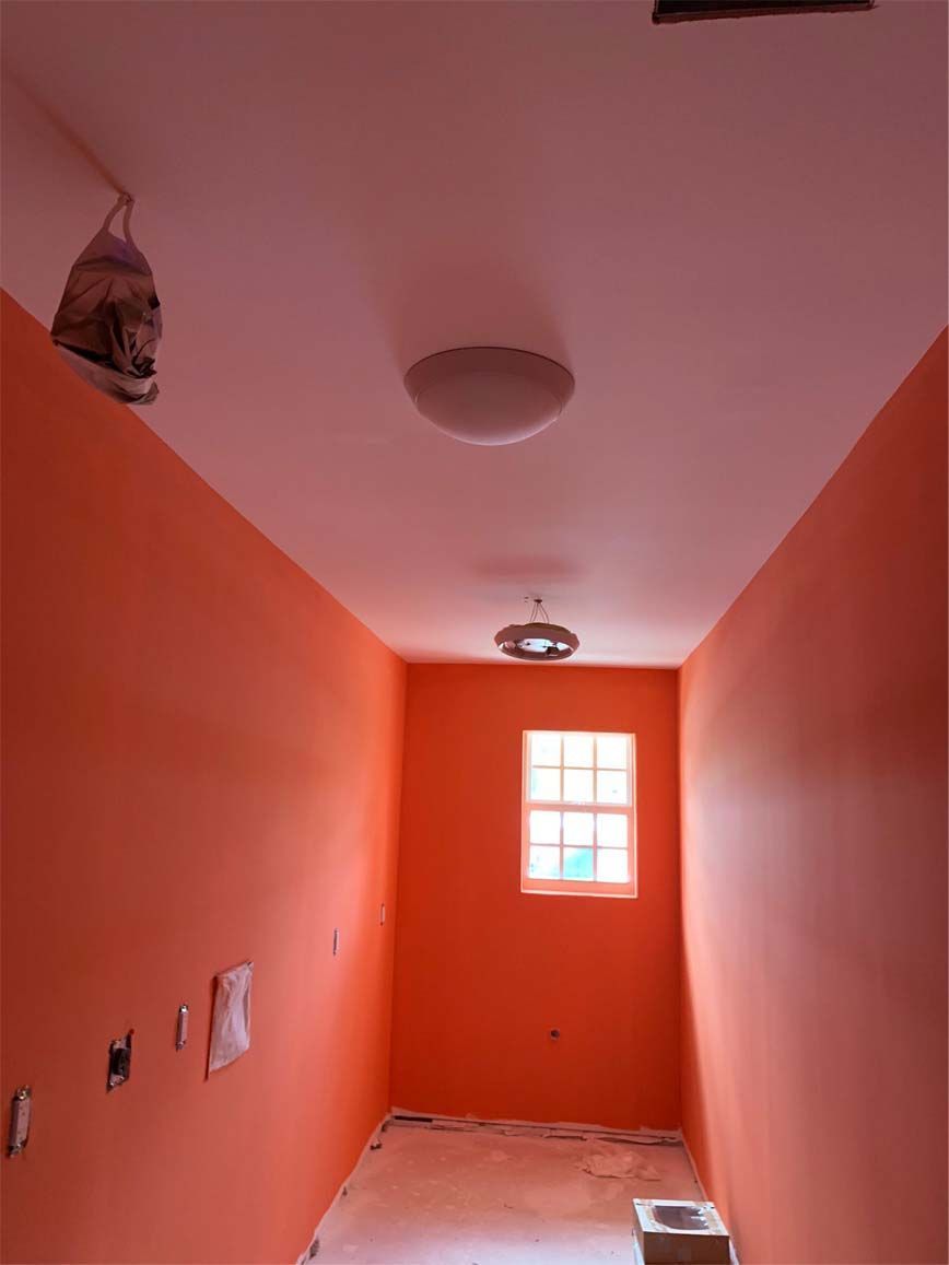 A narrow room with orange walls and a window.