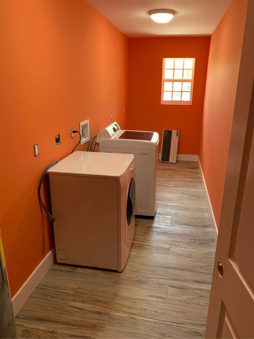 A laundry room with orange walls and a washer and dryer.
