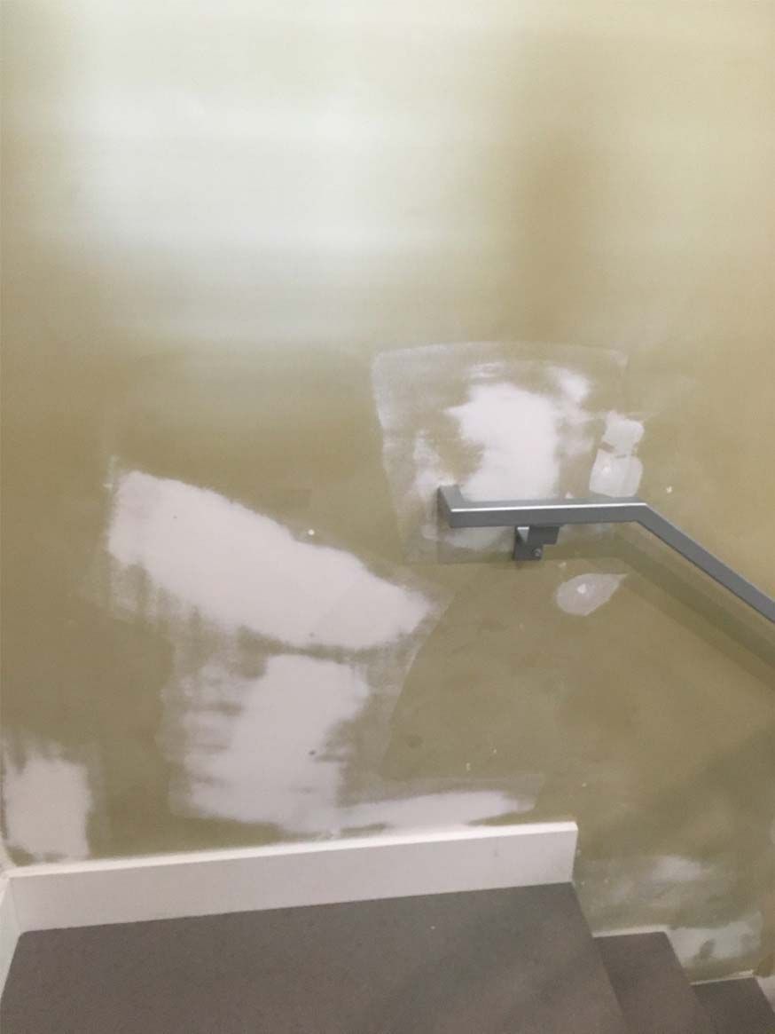 A staircase with a railing and a flooded wall.