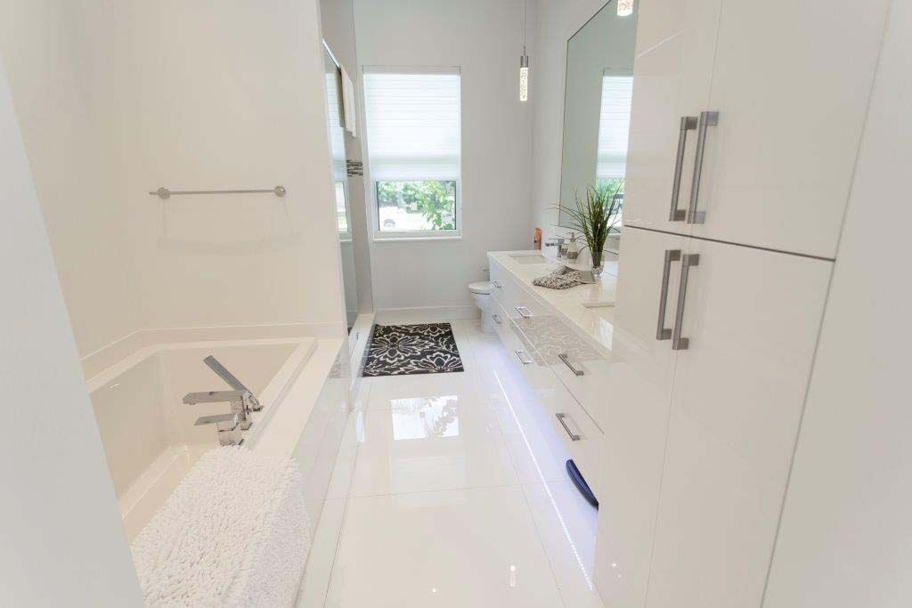 A bathroom with a tub , sink , mirror and cabinets.