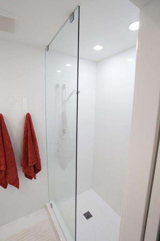 A bathroom with a walk in shower and two red towels hanging on the wall.