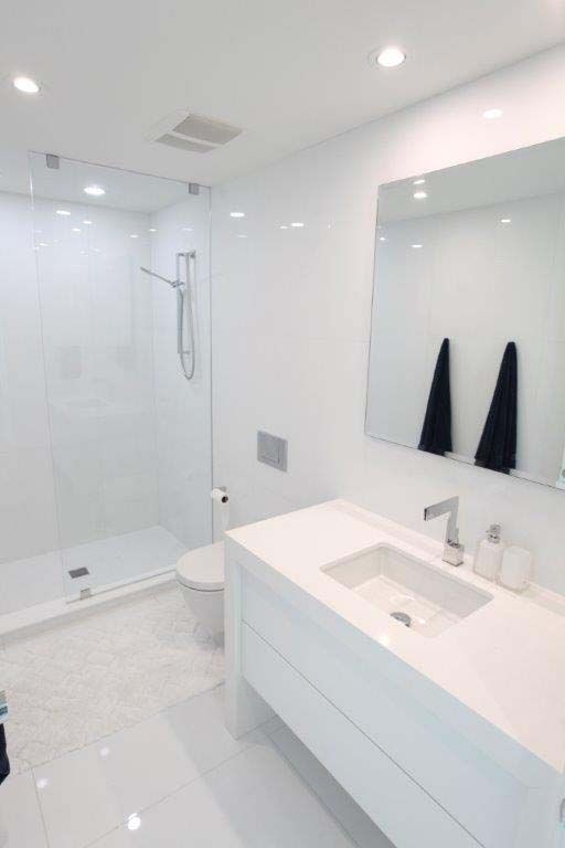 A bathroom with a sink , toilet , shower and mirror.